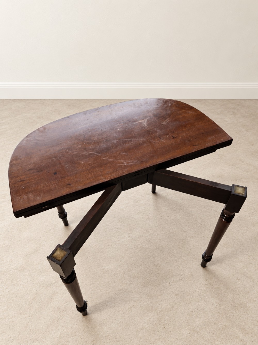 A Regency period mahogany fold-over table featuring a demilune top, flame mahogany frieze, and turned tapered legs with ring detailing. View VI