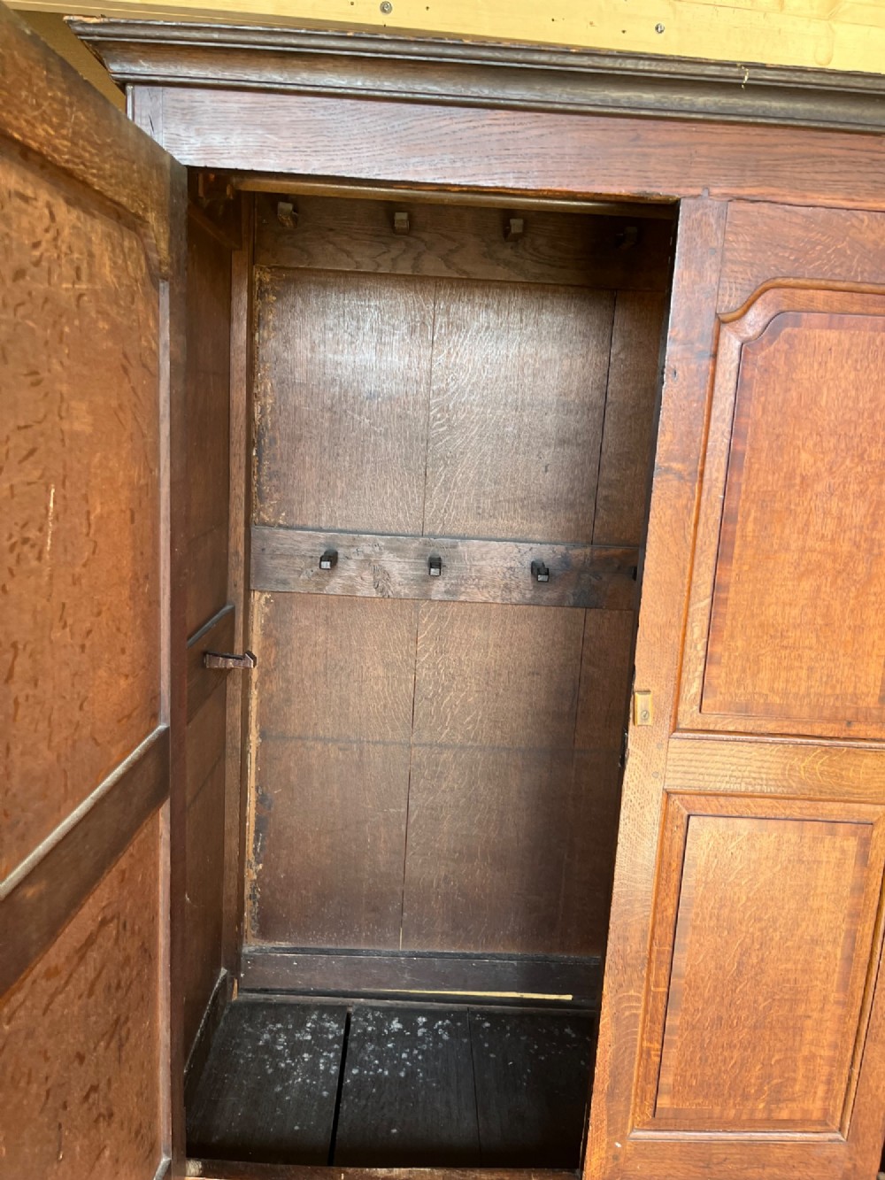 An early eighteenth-century warm brown oak housekeepers cupboard featuring three panelled upper doors over six lower drawers with brass drop handles. View VIII