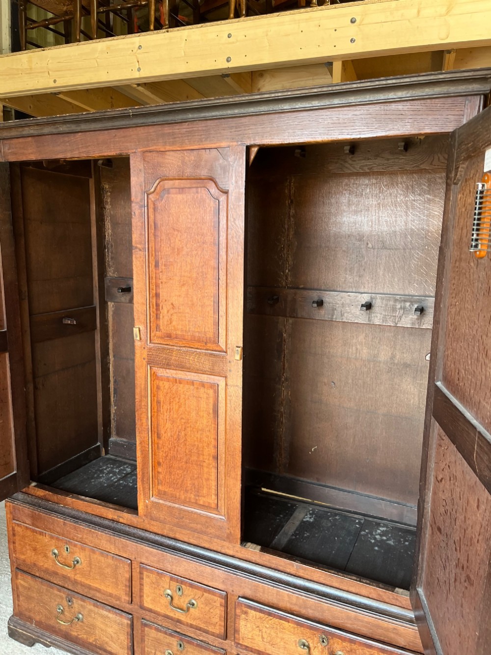 An early eighteenth-century warm brown oak housekeepers cupboard featuring three panelled upper doors over six lower drawers with brass drop handles. View IX