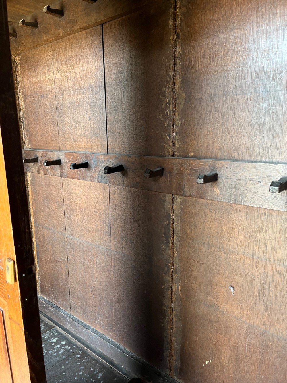 An early eighteenth-century warm brown oak housekeepers cupboard featuring three panelled upper doors over six lower drawers with brass drop handles. View X