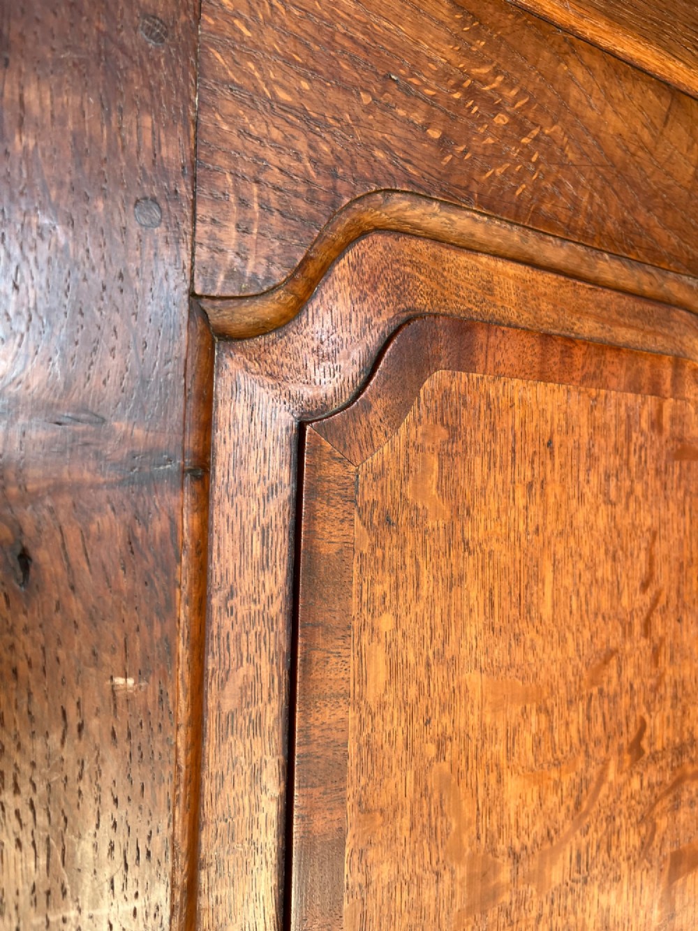 An early eighteenth-century warm brown oak housekeepers cupboard featuring three panelled upper doors over six lower drawers with brass drop handles. View XI