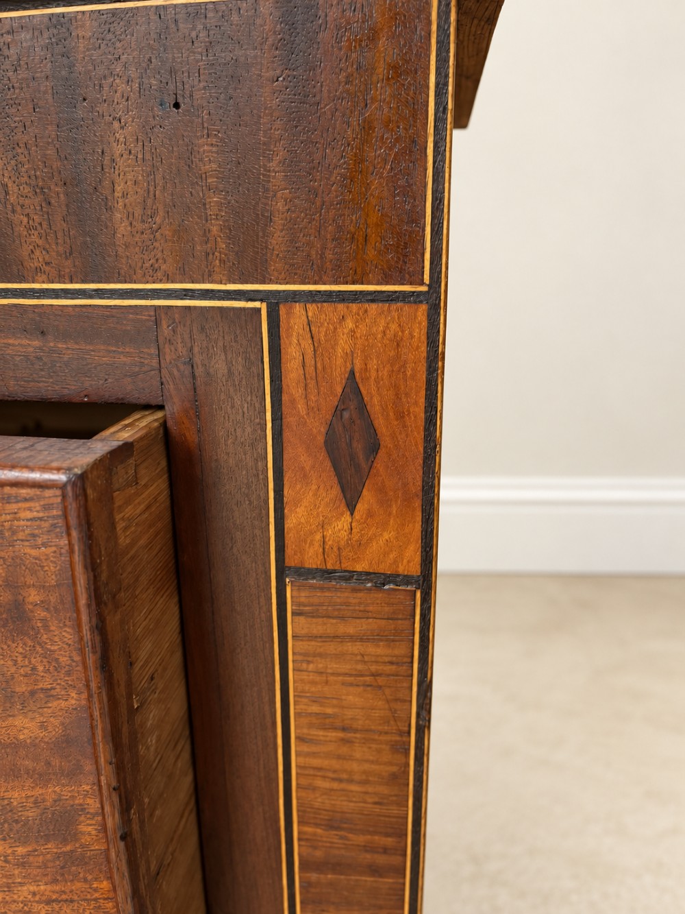 A Georgian mahogany cupboard on chest featuring upper double panelled doors with flame veneer, decorative cresting, and a lower chest of drawers on turned feet. View IV