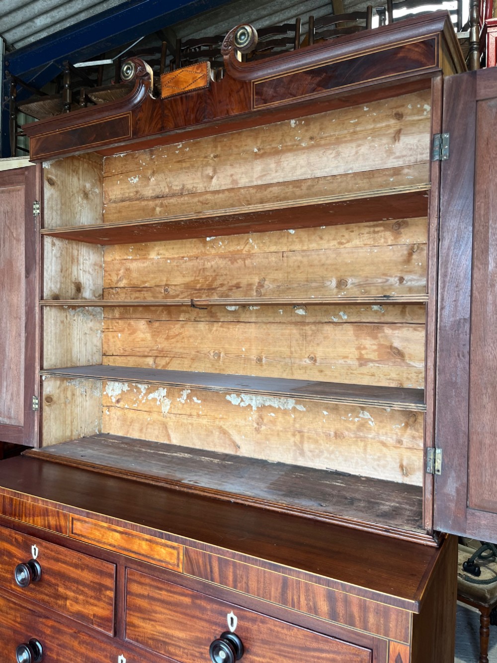 A Georgian mahogany cupboard on chest featuring upper double panelled doors with flame veneer, decorative cresting, and a lower chest of drawers on turned feet. View VIII
