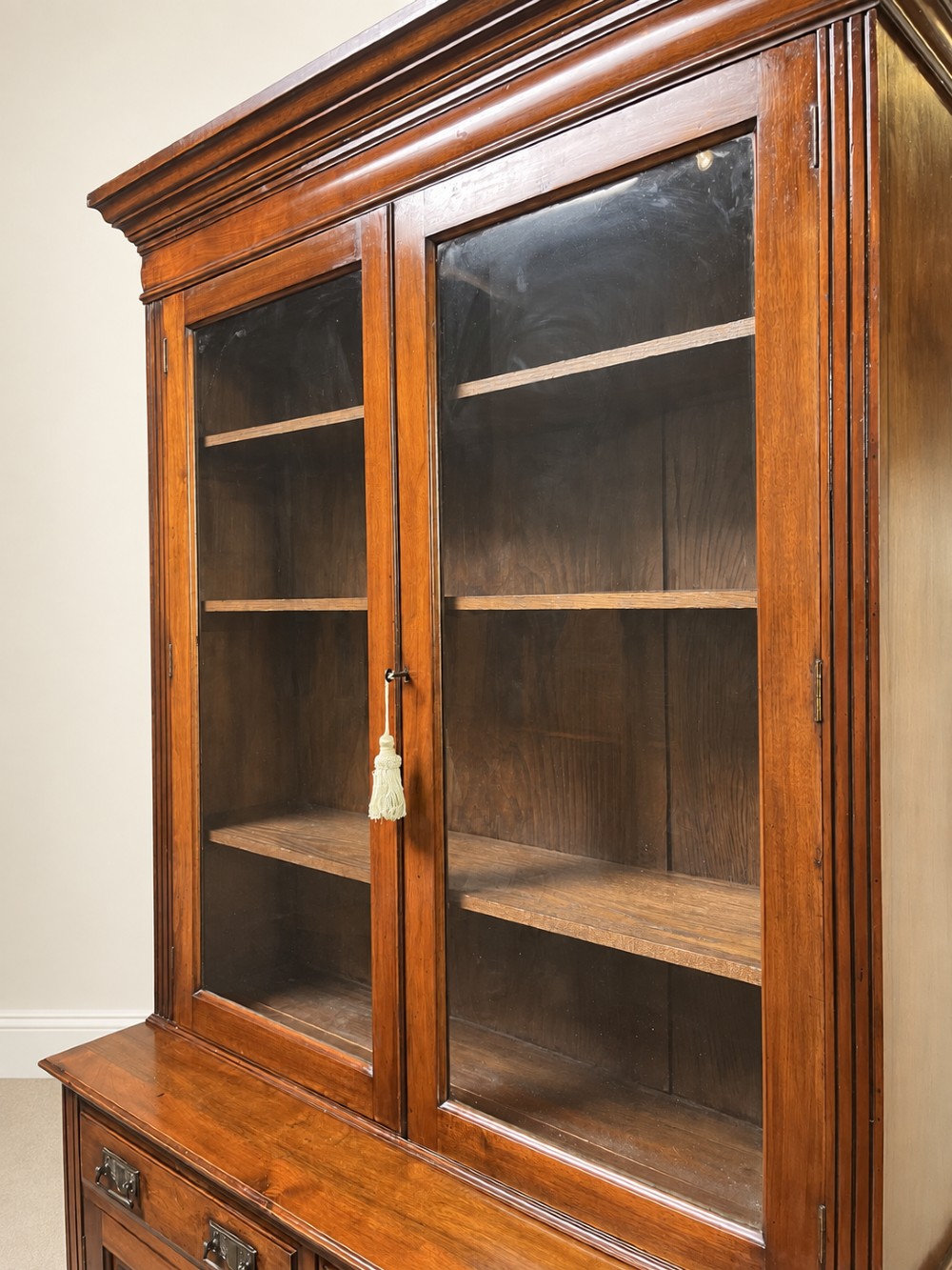 A late nineteenth-century mahogany bookcase featuring two glass-front upper doors above two drawers and a double cupboard base. View VI