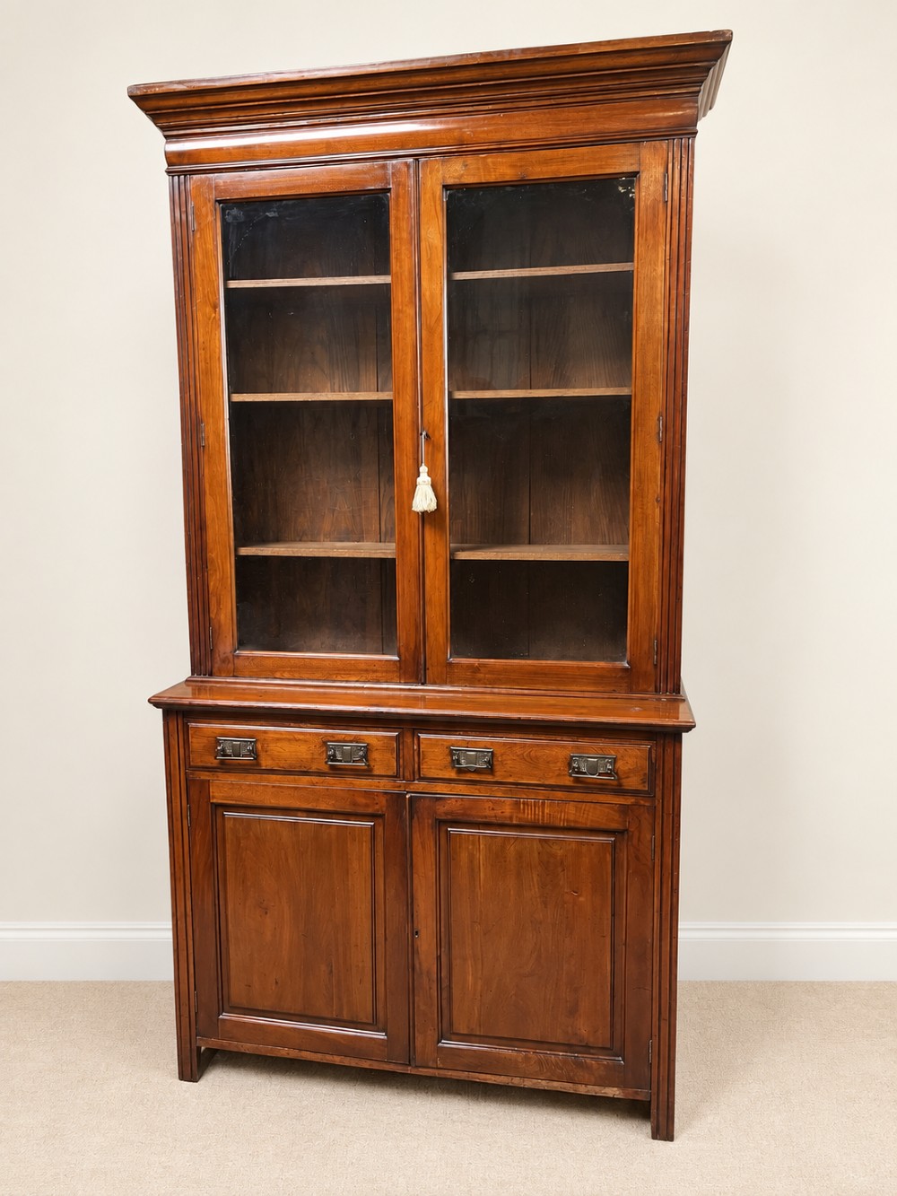 A late nineteenth-century mahogany bookcase featuring two glass-front upper doors above two drawers and a double cupboard base. View XI