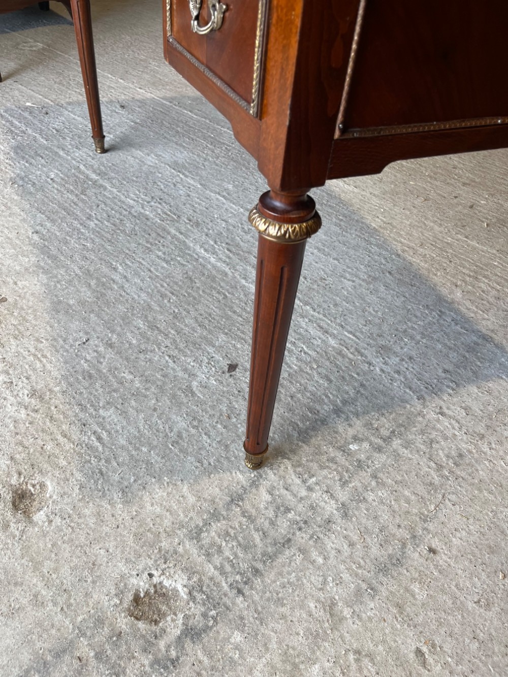 A French Louis XVI style mahogany writing desk featuring a brown leather top, five drawers with cast brass handles, and gilt bronze mounts on fluted tapering legs. View IV