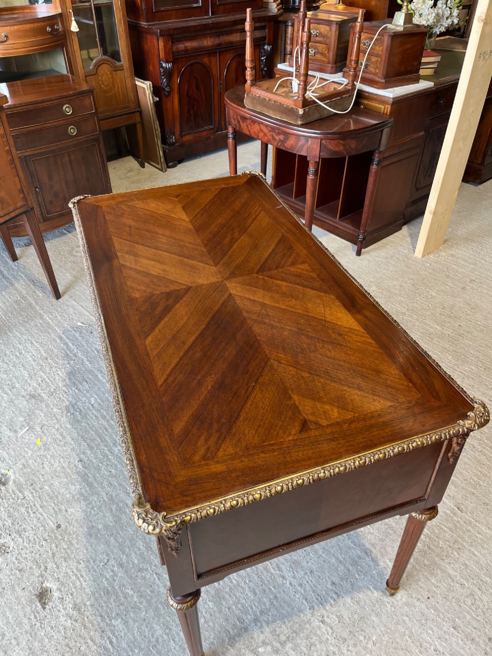 A French Louis XVI style mahogany writing desk featuring a brown leather top, five drawers with cast brass handles, and gilt bronze mounts on fluted tapering legs. View VI