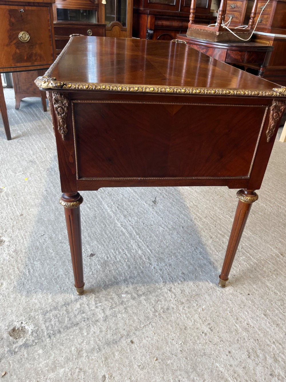 A French Louis XVI style mahogany writing desk featuring a brown leather top, five drawers with cast brass handles, and gilt bronze mounts on fluted tapering legs. View VIII