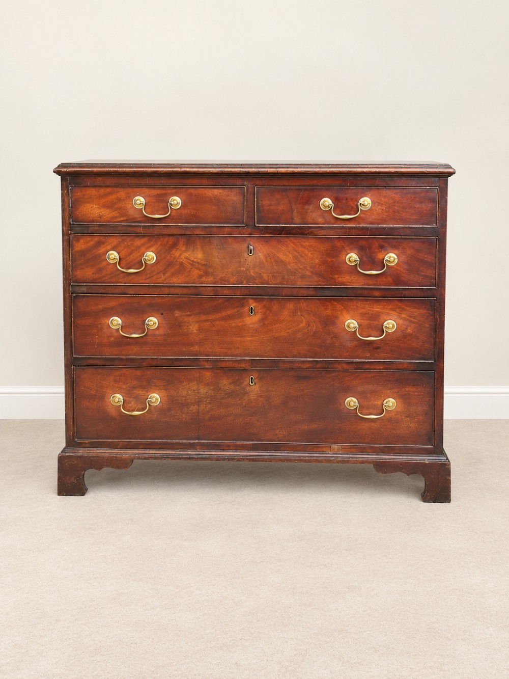 A Georgian mahogany chest of drawers featuring two short drawers above three long drawers with brass swan-neck handles, raised on bracket feet.