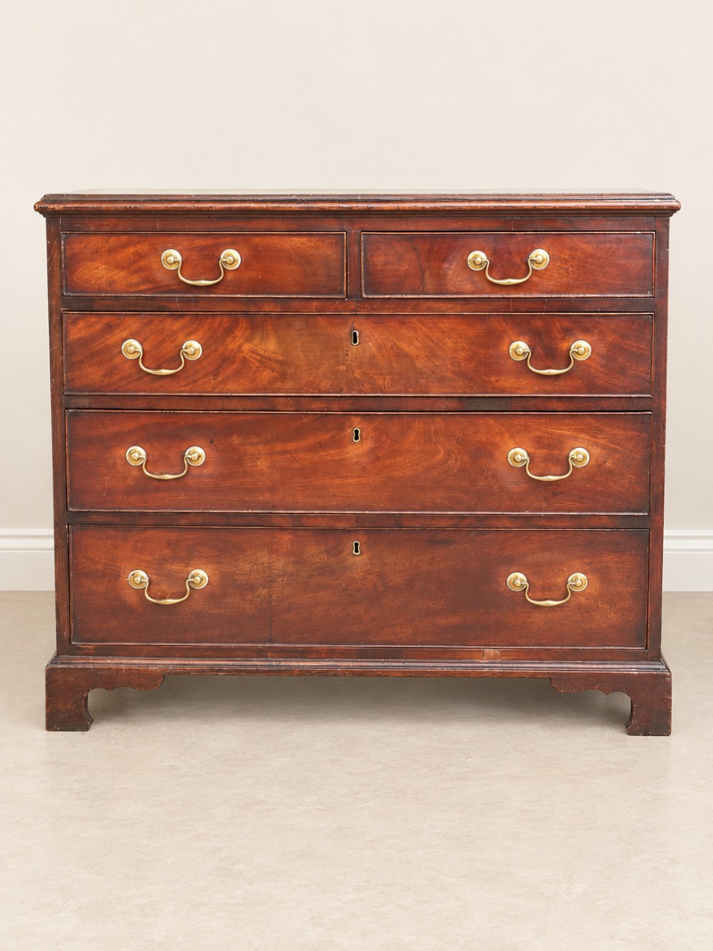 A Georgian mahogany chest of drawers featuring two short drawers above three long drawers with brass swan-neck handles, raised on bracket feet. View III