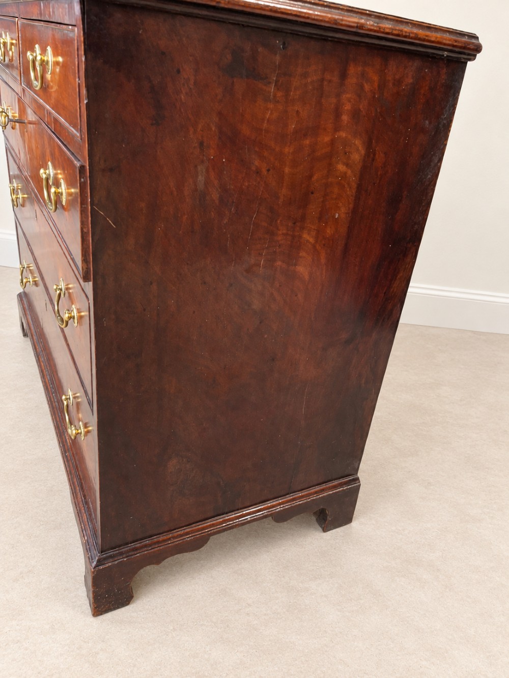A Georgian mahogany chest of drawers featuring two short drawers above three long drawers with brass swan-neck handles, raised on bracket feet. View VIII
