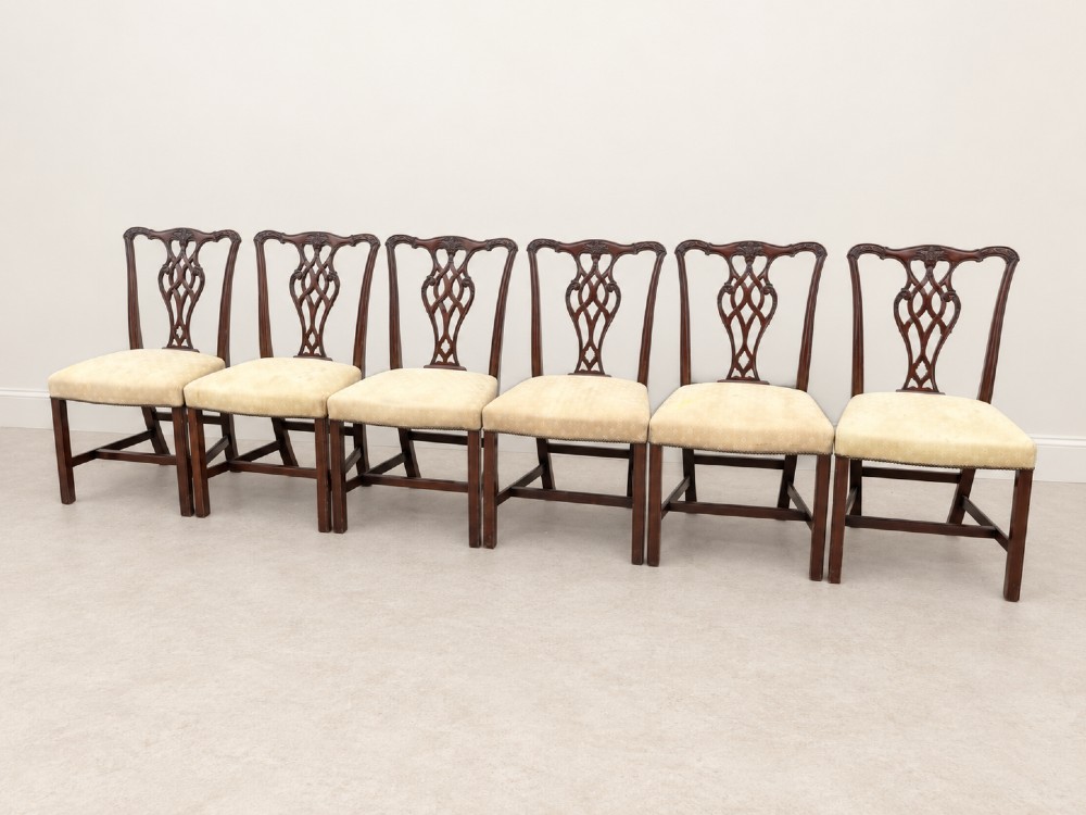 A set of six Chippendale style mahogany dining chairs featuring intricately carved pierced back splats and cream upholstered seats. View II