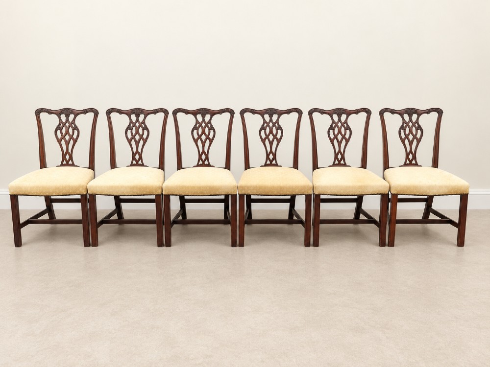 A set of six Chippendale style mahogany dining chairs featuring intricately carved pierced back splats and cream upholstered seats. View IV