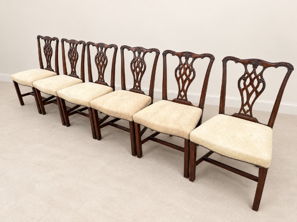 A set of six Chippendale style mahogany dining chairs featuring intricately carved pierced back splats and cream upholstered seats. View V