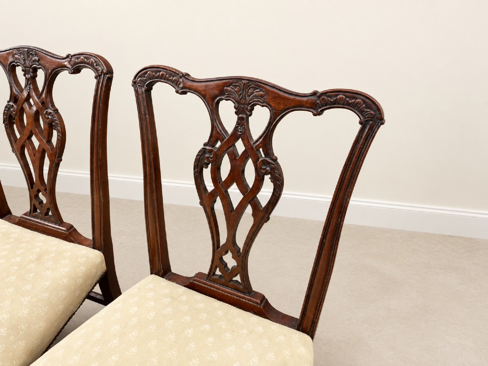 A set of six Chippendale style mahogany dining chairs featuring intricately carved pierced back splats and cream upholstered seats. View VI