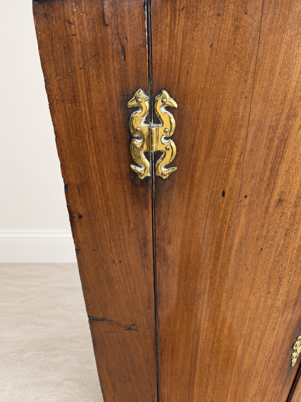 An antique Georgian mahogany corner cupboard featuring a curved bowfront double-door structure with ornate brass hinges and moulding. View V