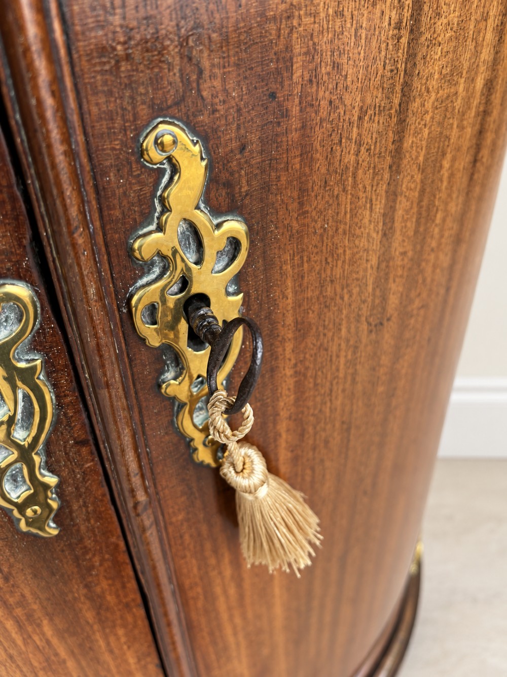 An antique Georgian mahogany corner cupboard featuring a curved bowfront double-door structure with ornate brass hinges and moulding. View VII