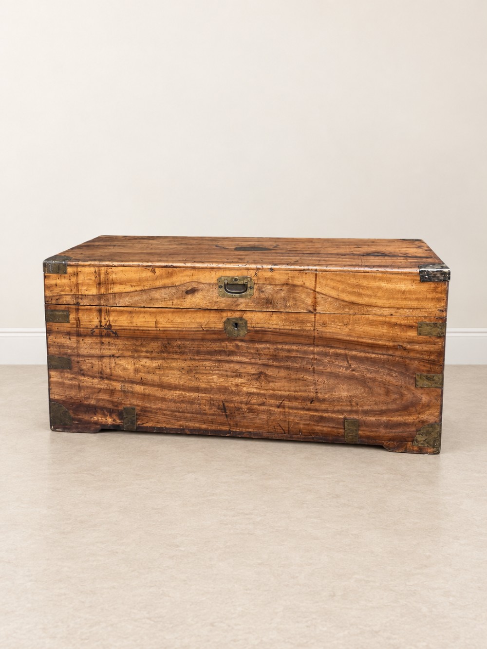 A 19th-century rectangular wooden campaign chest featuring protective brass corner brackets, flush carrying handles, and a hinged lid.