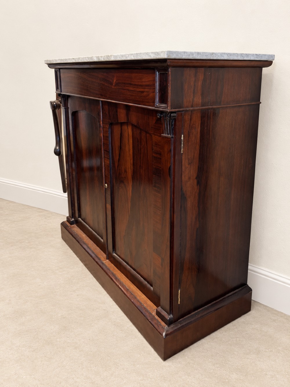 A pair of 19th-century Regency dark rosewood cupboards featuring white marble tops and panelled double doors on plinth bases. View II