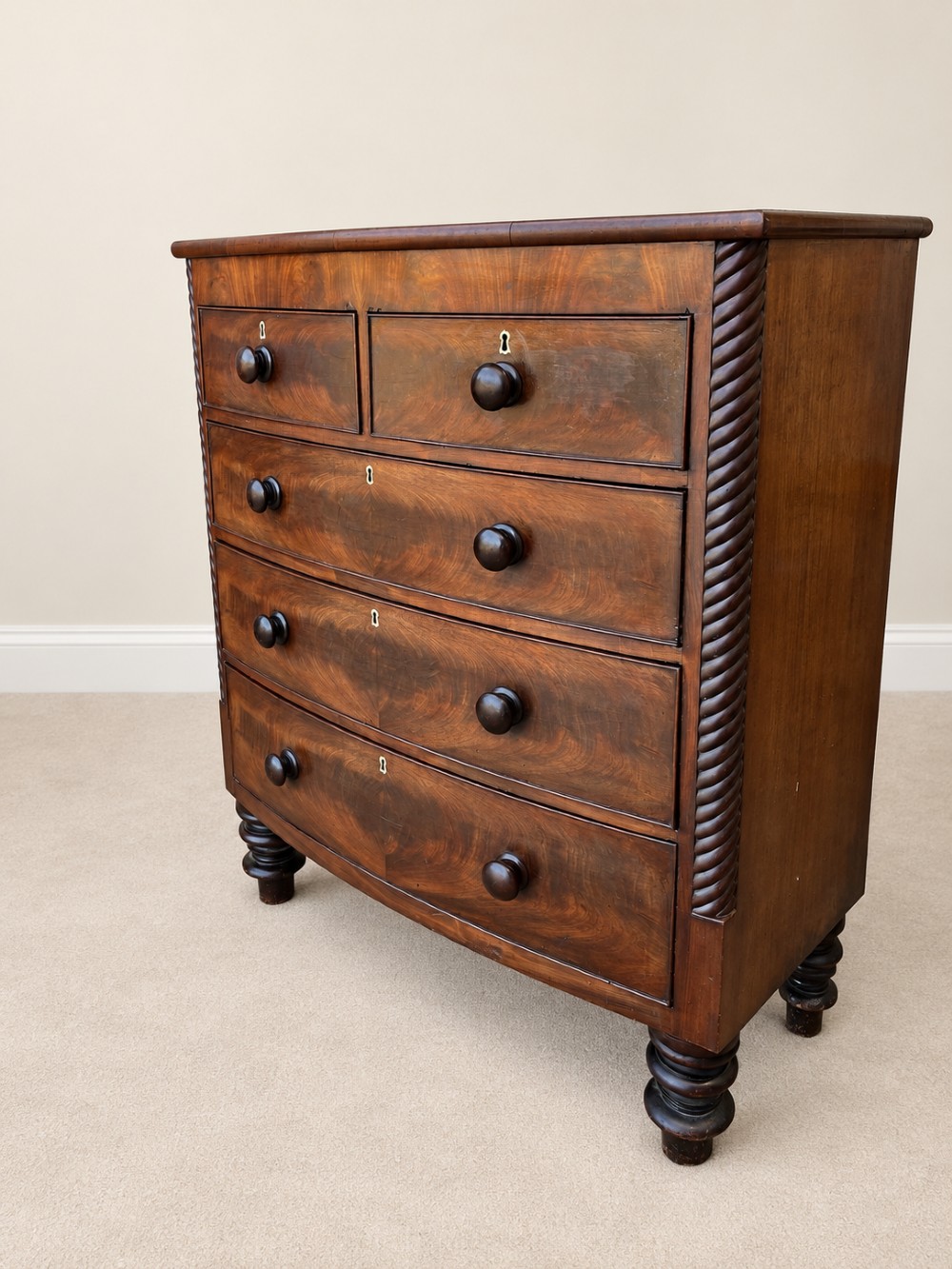 A 19th-century mahogany bowfront chest of drawers featuring spiral rope-twist pilasters, turned wooden knobs, and brass keyhole escutcheons. View III