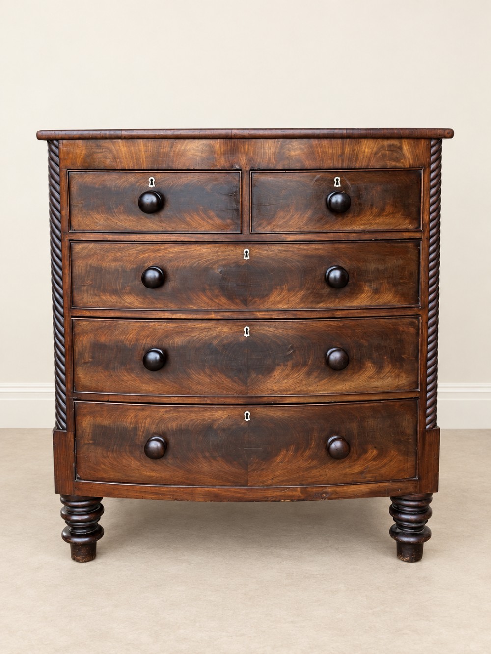 A 19th-century mahogany bowfront chest of drawers featuring spiral rope-twist pilasters, turned wooden knobs, and brass keyhole escutcheons. View IV