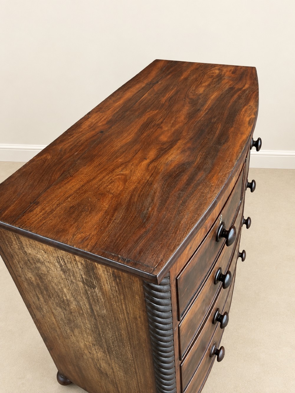 A 19th-century mahogany bowfront chest of drawers featuring spiral rope-twist pilasters, turned wooden knobs, and brass keyhole escutcheons. View V