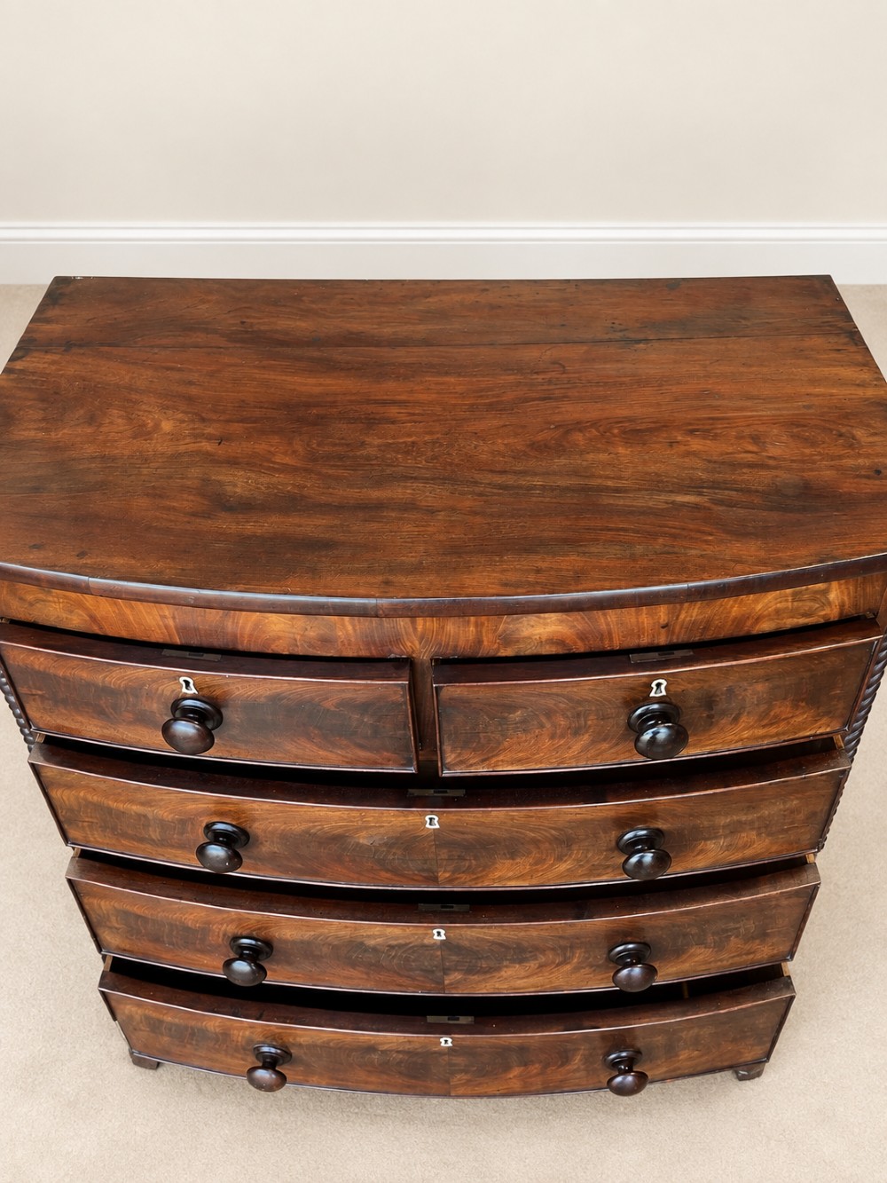 A 19th-century mahogany bowfront chest of drawers featuring spiral rope-twist pilasters, turned wooden knobs, and brass keyhole escutcheons. View VIII
