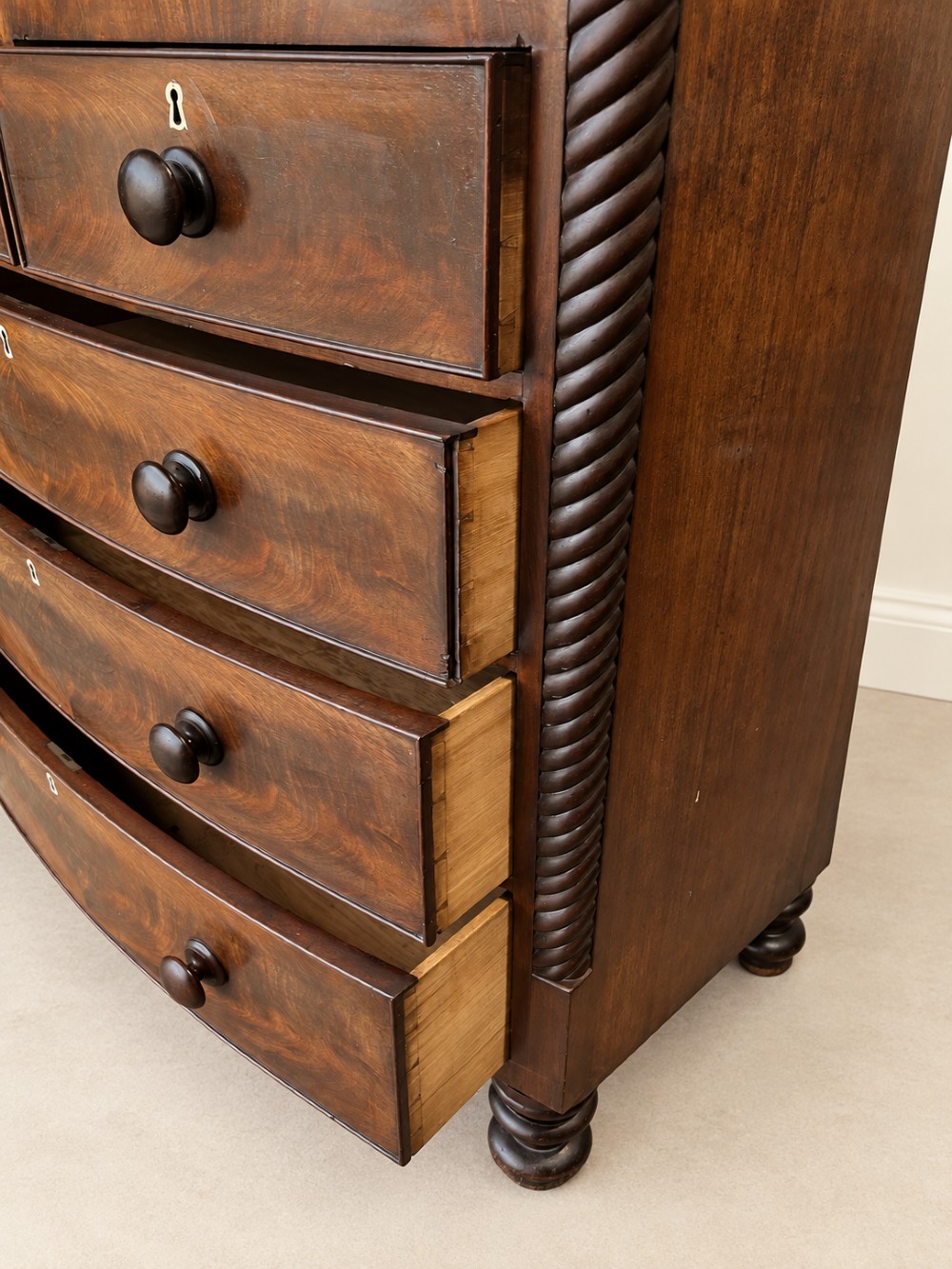 A 19th-century mahogany bowfront chest of drawers featuring spiral rope-twist pilasters, turned wooden knobs, and brass keyhole escutcheons. View IX