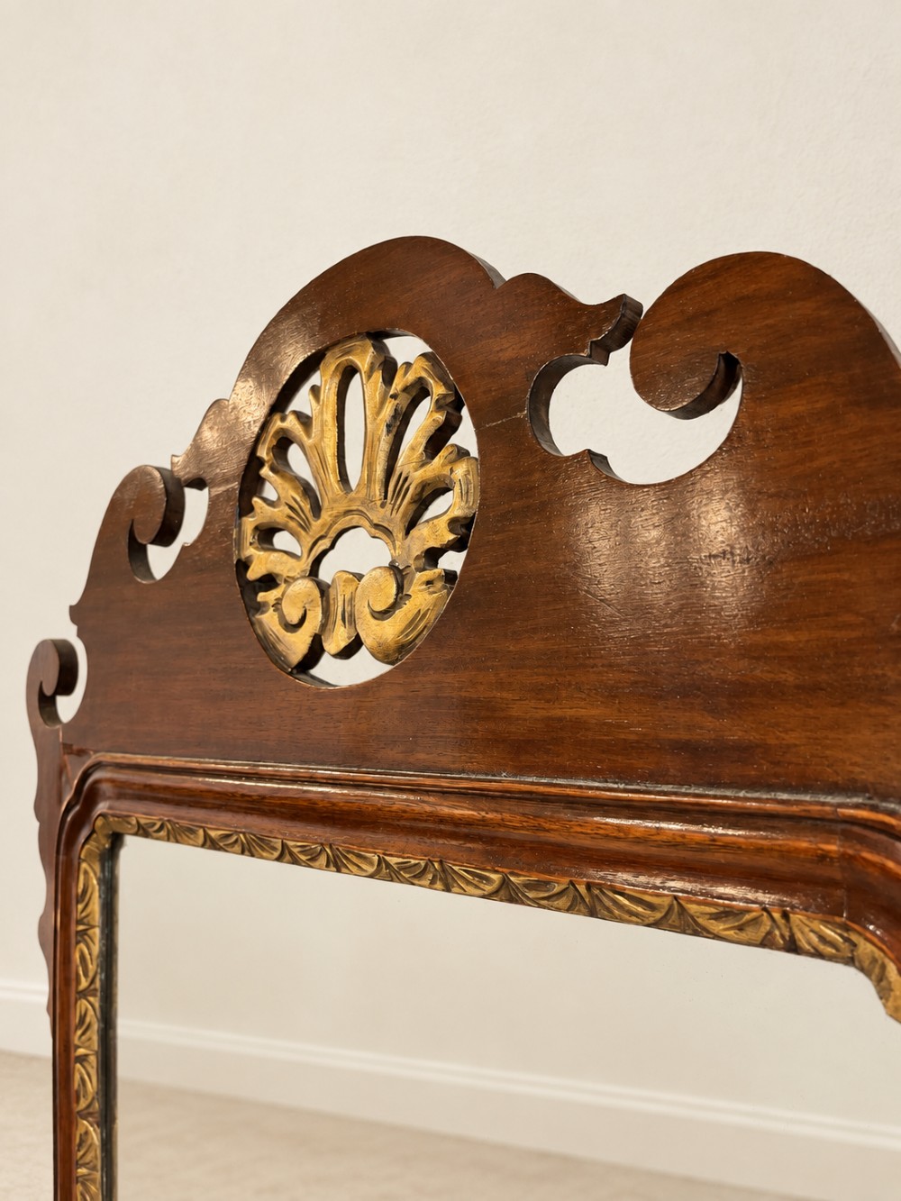 A Georgian mahogany fretwork wall mirror featuring a scrollwork frame, gilt shell cresting detail, and a gilded inner border. View V