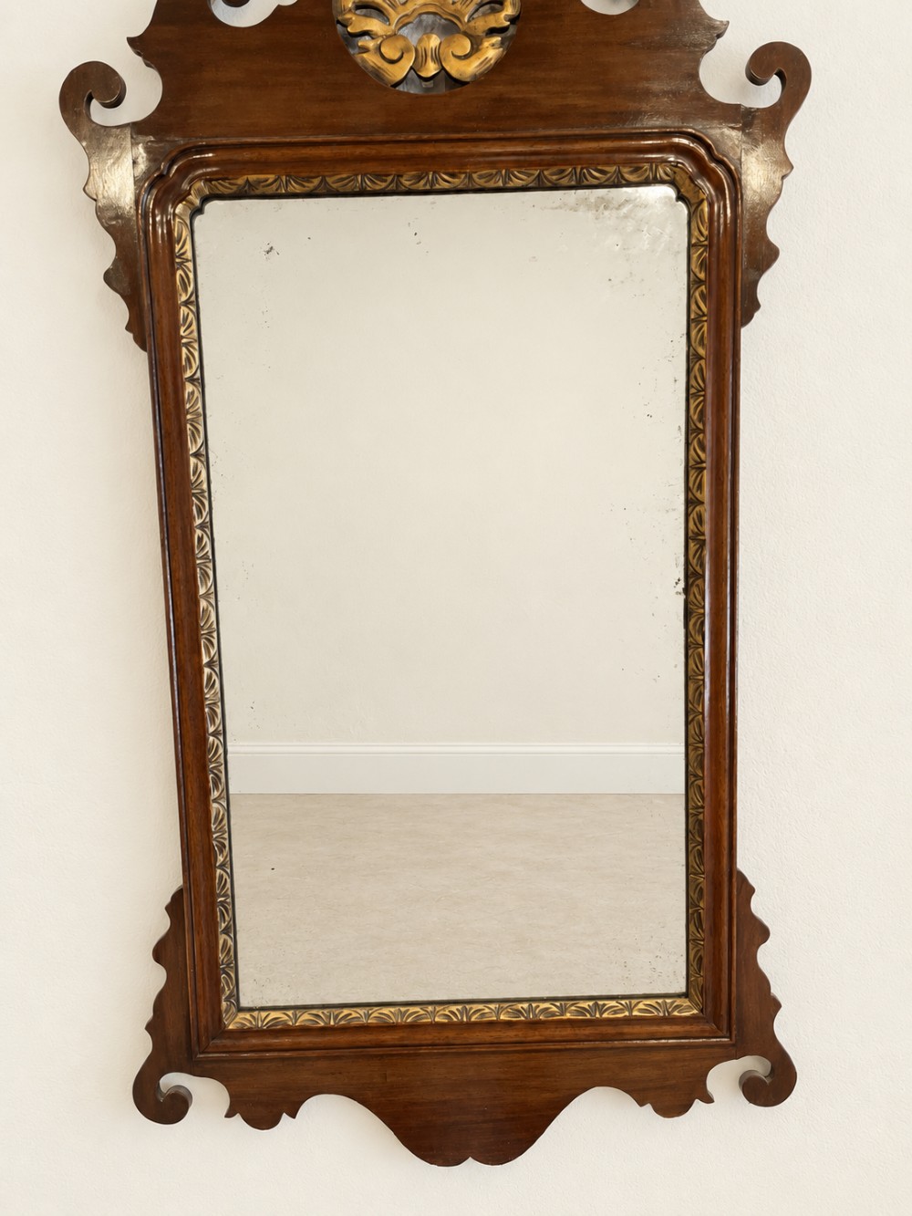 A Georgian mahogany fretwork wall mirror featuring a scrollwork frame, gilt shell cresting detail, and a gilded inner border. View VII