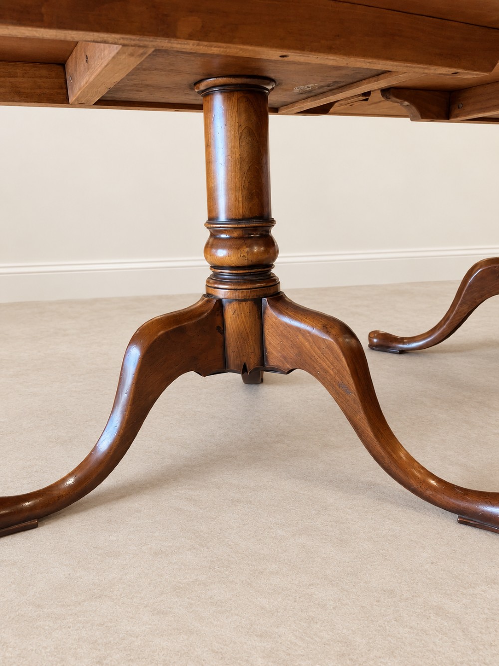 A large extendable mahogany dining table surrounded by ten matching wooden chairs with patterned pink fabric seats. View V