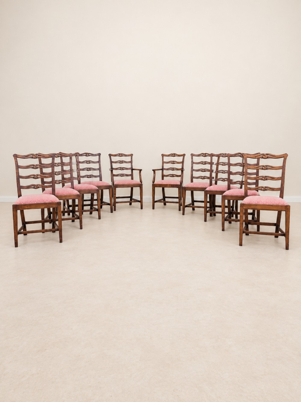 A large extendable mahogany dining table surrounded by ten matching wooden chairs with patterned pink fabric seats. View VII