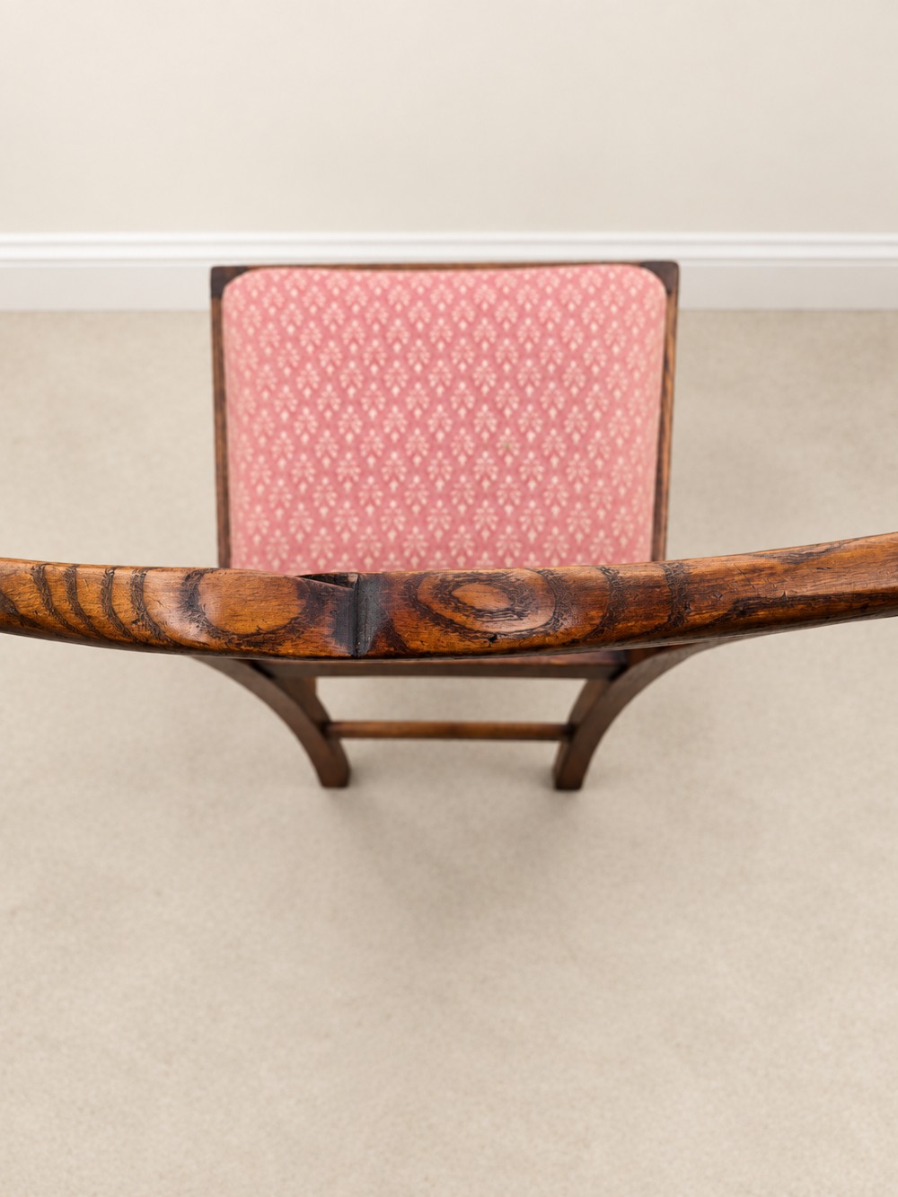 A large extendable mahogany dining table surrounded by ten matching wooden chairs with patterned pink fabric seats. View XI