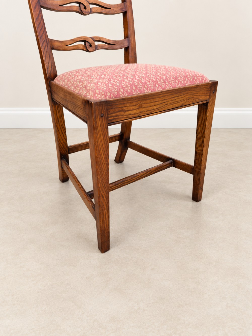 A large extendable mahogany dining table surrounded by ten matching wooden chairs with patterned pink fabric seats. View XIII