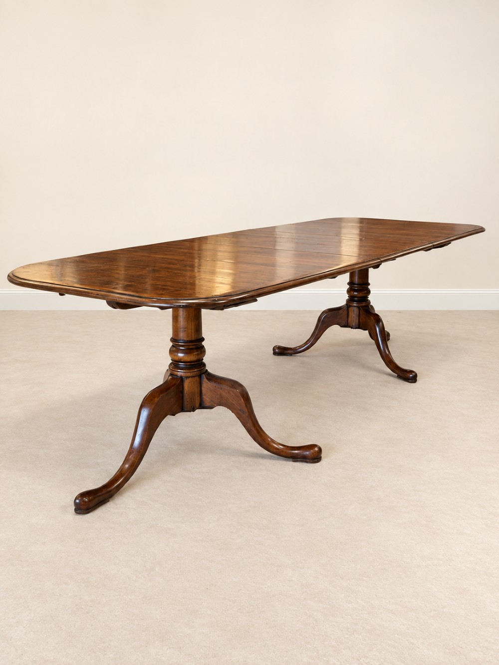 A large extendable mahogany dining table surrounded by ten matching wooden chairs with patterned pink fabric seats. View XIV
