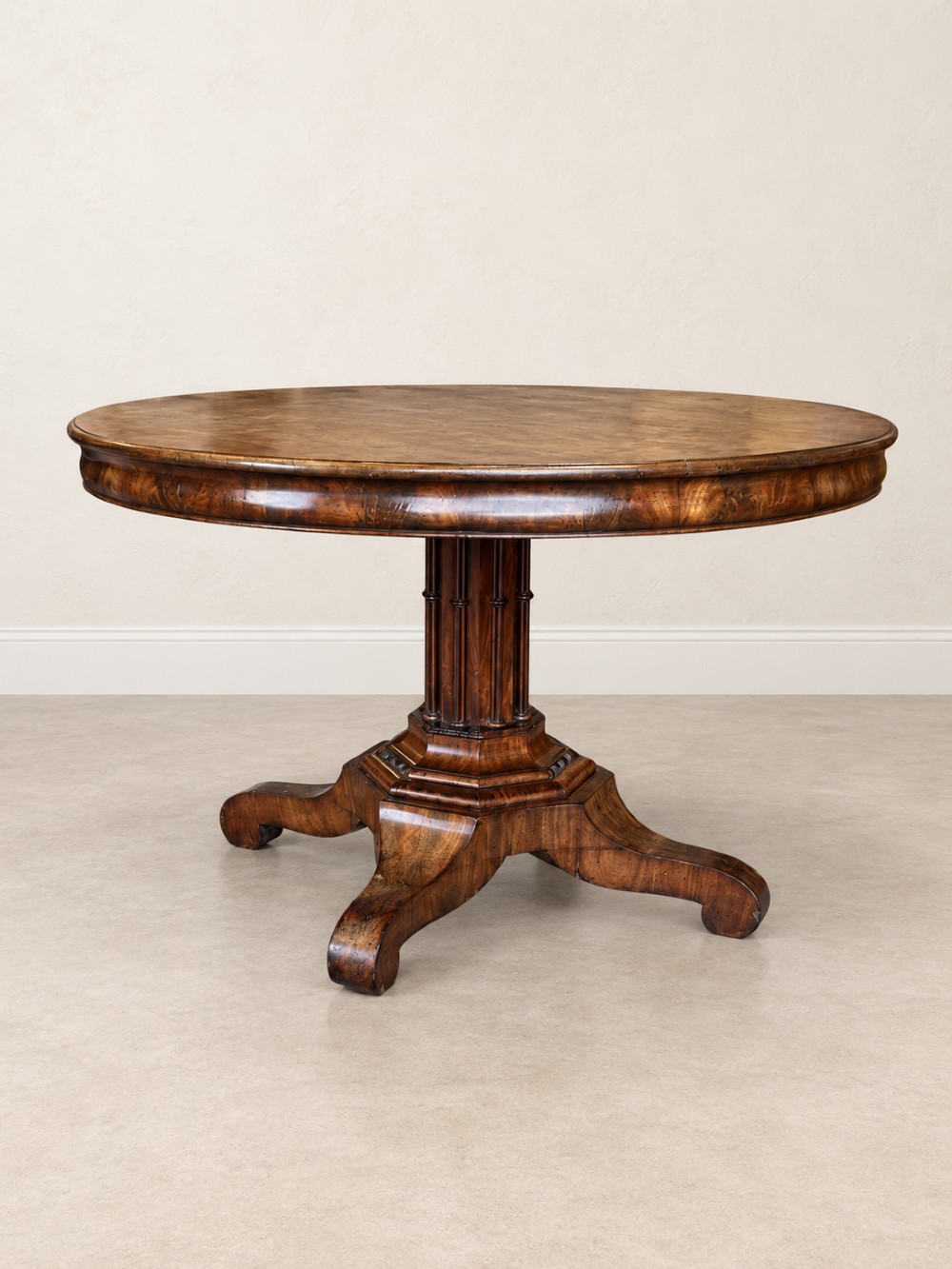 A 19th-century circular mahogany dining table featuring a figured grain top, fluted central pedestal column, and a quadform platform base on scroll feet. View II