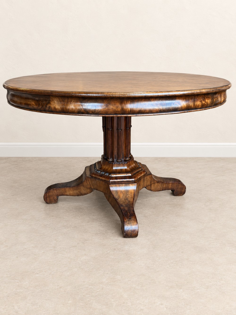 A 19th-century circular mahogany dining table featuring a figured grain top, fluted central pedestal column, and a quadform platform base on scroll feet. View V