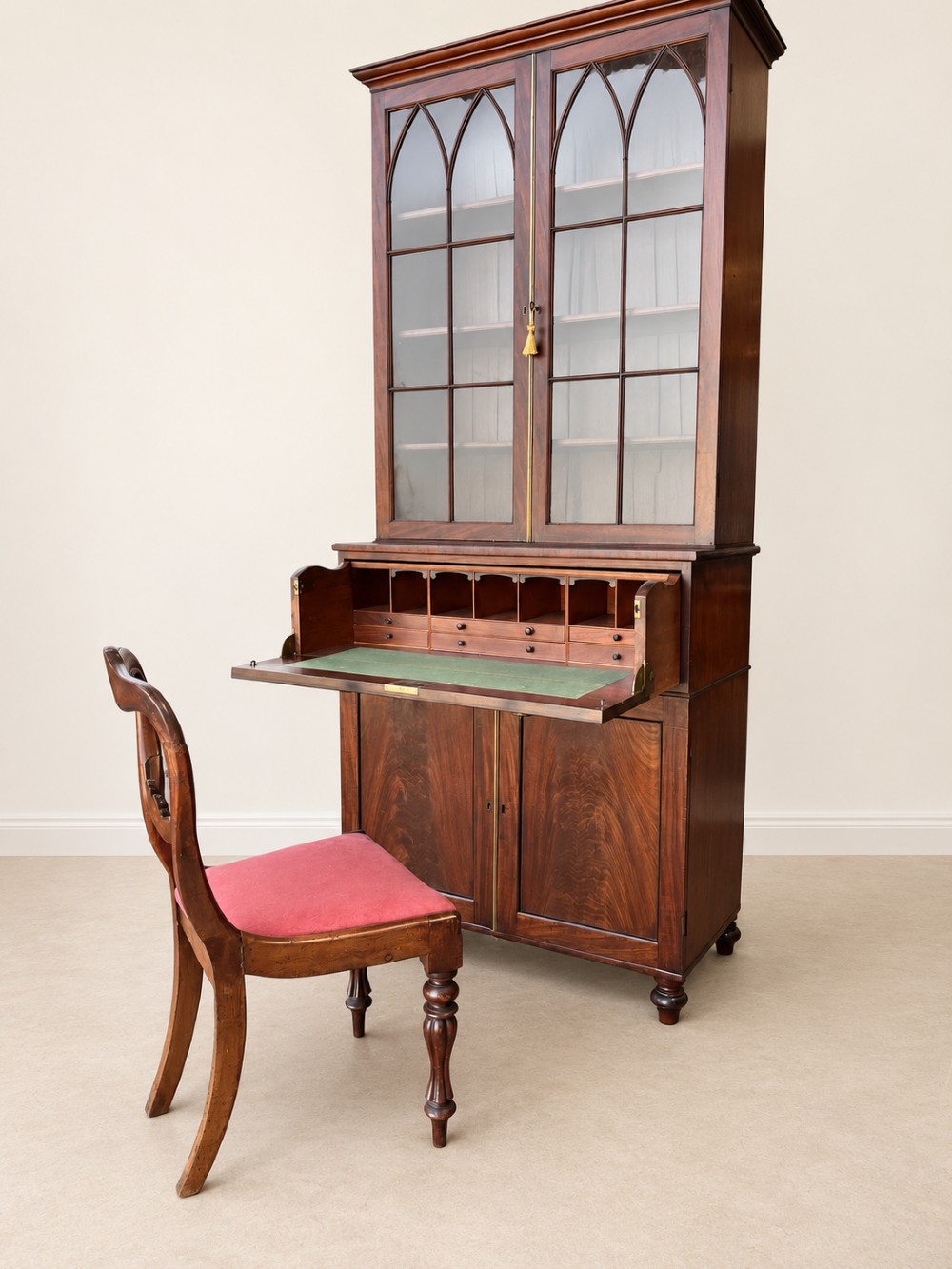 A tall 19th-century mahogany secretaire bookcase featuring upper glazed doors with Gothic arched astragal glazing, a deep drawer, and a lower two-door cupboard standing on turned feet. View IX