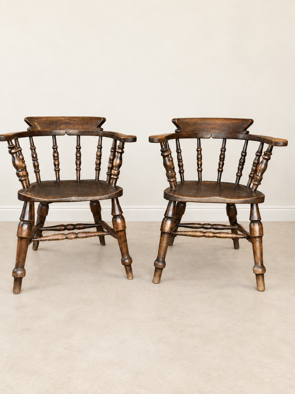 A pair of 19th-century dark wood captains chairs featuring turned spindles, contoured saddle seats, and turned legs joined by stretchers. View VI