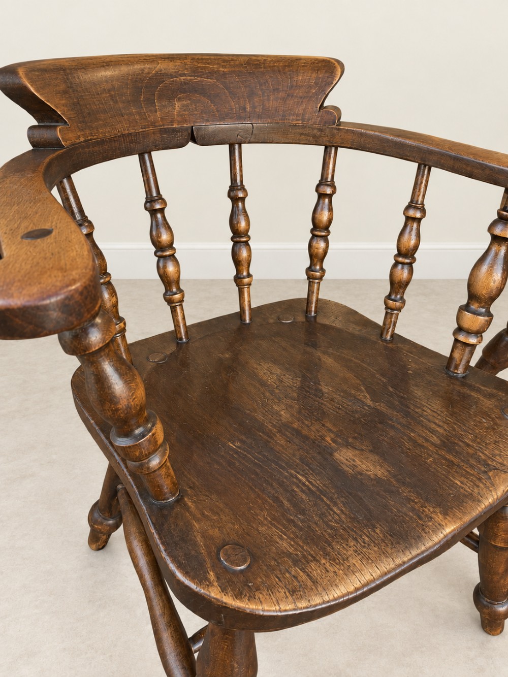 A pair of 19th-century dark wood captains chairs featuring turned spindles, contoured saddle seats, and turned legs joined by stretchers. View VII