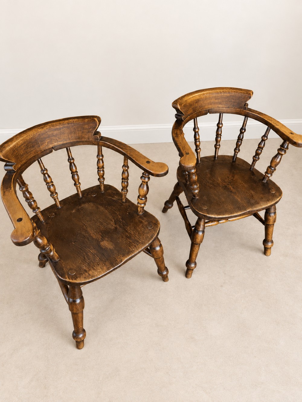 A pair of 19th-century dark wood captains chairs featuring turned spindles, contoured saddle seats, and turned legs joined by stretchers. View VIII