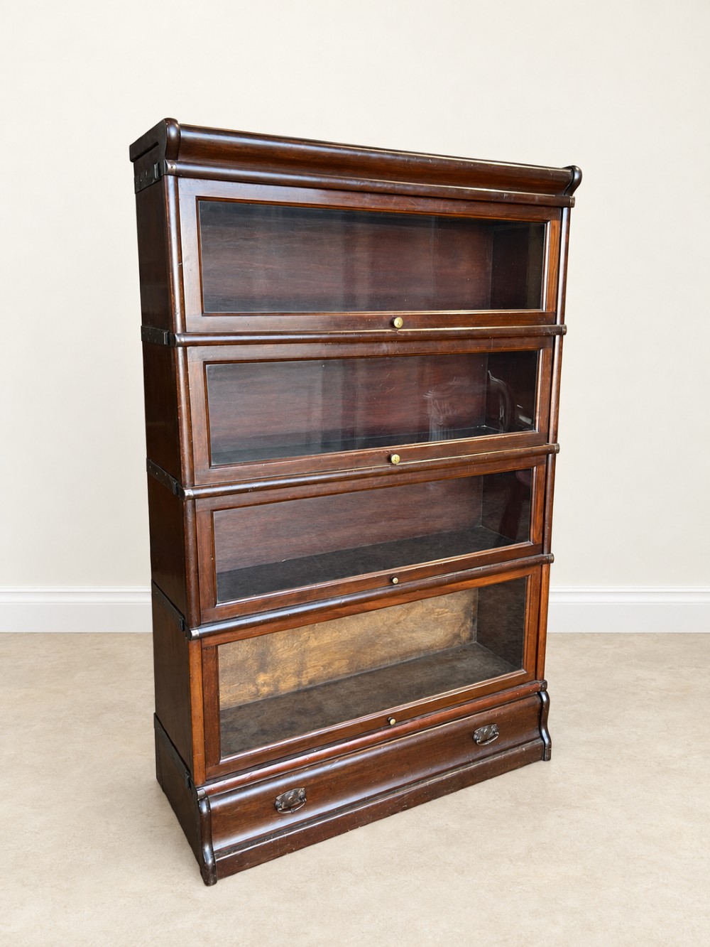 A four-tier dark mahogany Globe Wernicke sectional bookcase featuring glazed lift-up doors and a bottom drawer with brass handles. View II