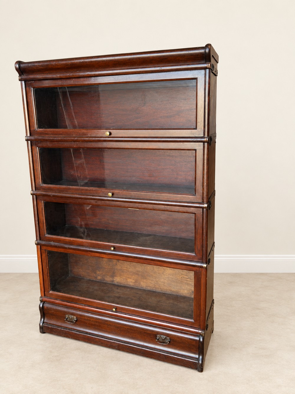 A four-tier dark mahogany Globe Wernicke sectional bookcase featuring glazed lift-up doors and a bottom drawer with brass handles. View III