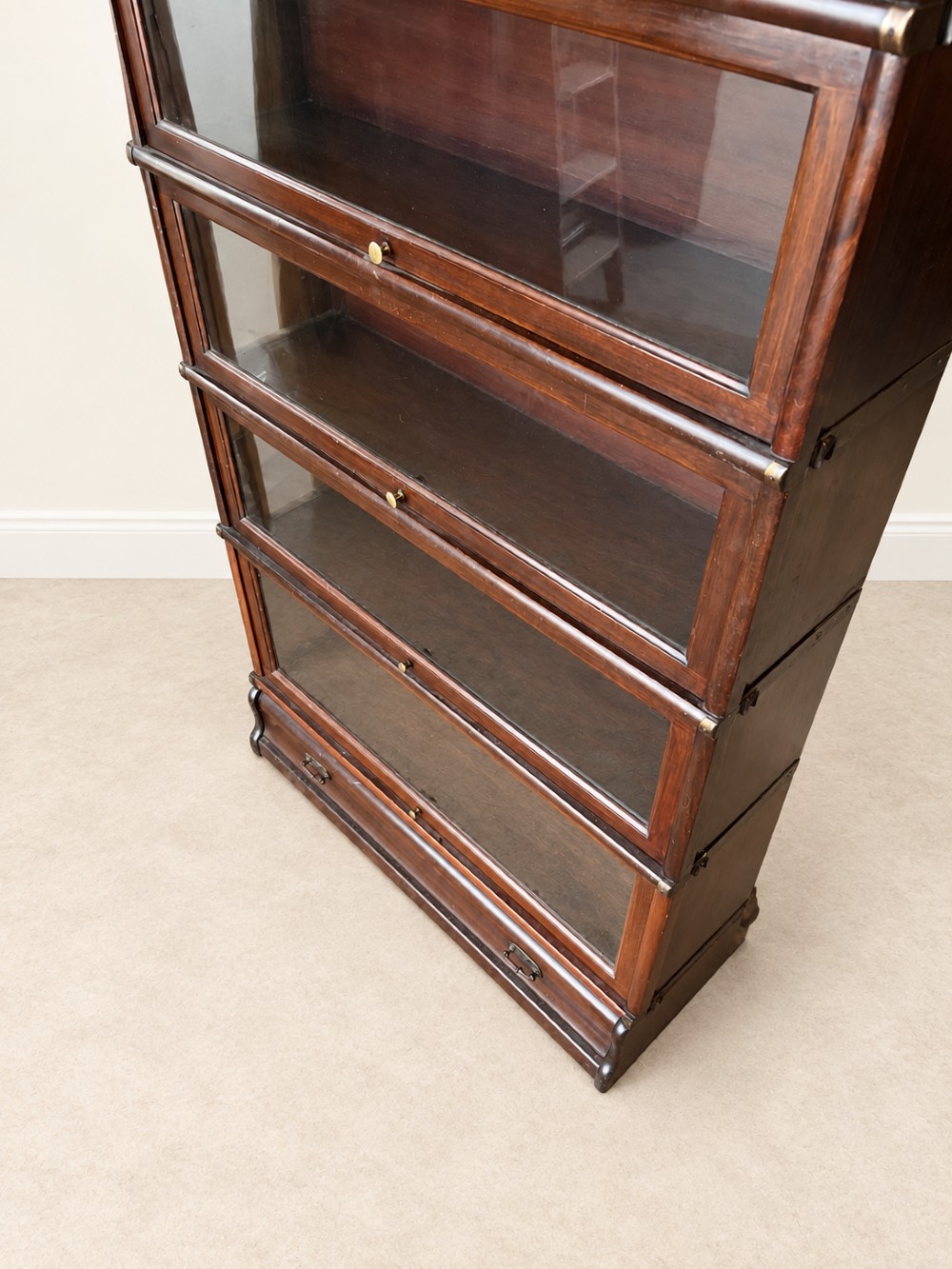 A four-tier dark mahogany Globe Wernicke sectional bookcase featuring glazed lift-up doors and a bottom drawer with brass handles. View VI