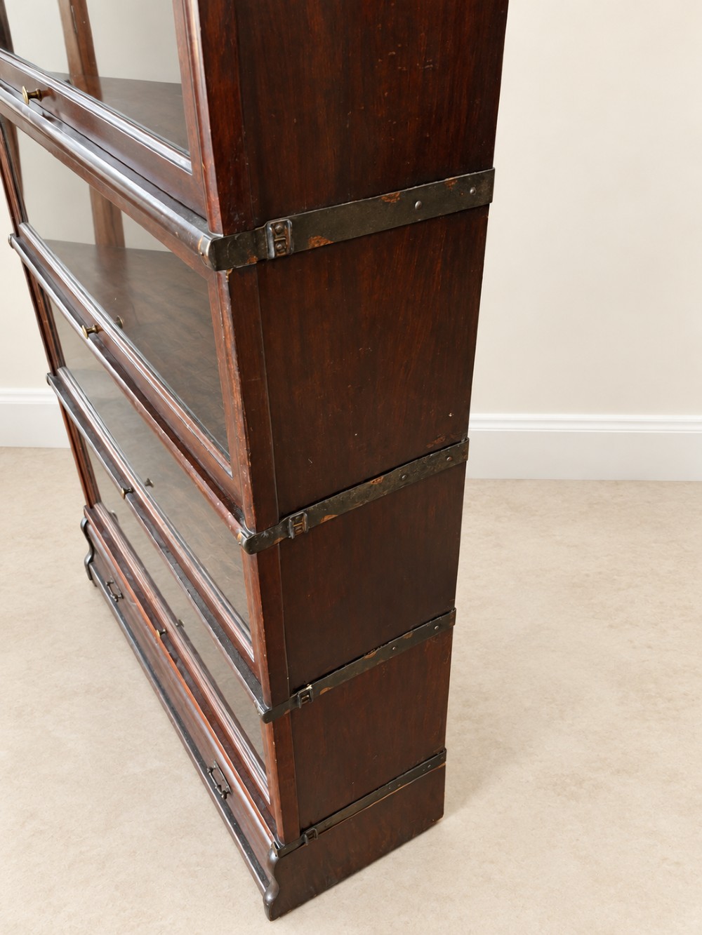 A four-tier dark mahogany Globe Wernicke sectional bookcase featuring glazed lift-up doors and a bottom drawer with brass handles. View XI
