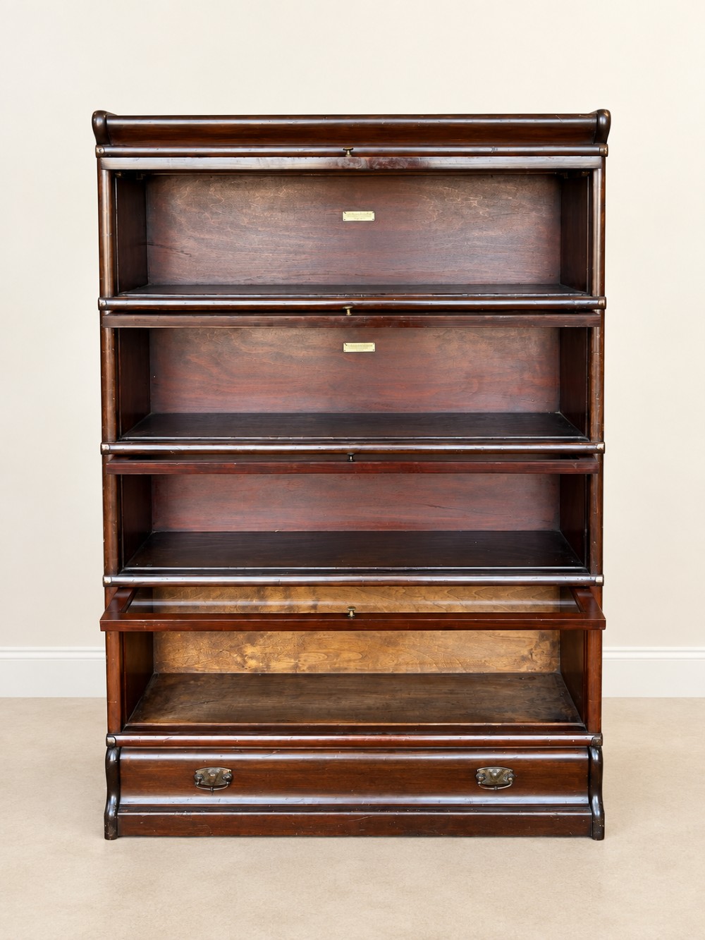 A four-tier dark mahogany Globe Wernicke sectional bookcase featuring glazed lift-up doors and a bottom drawer with brass handles. View XII