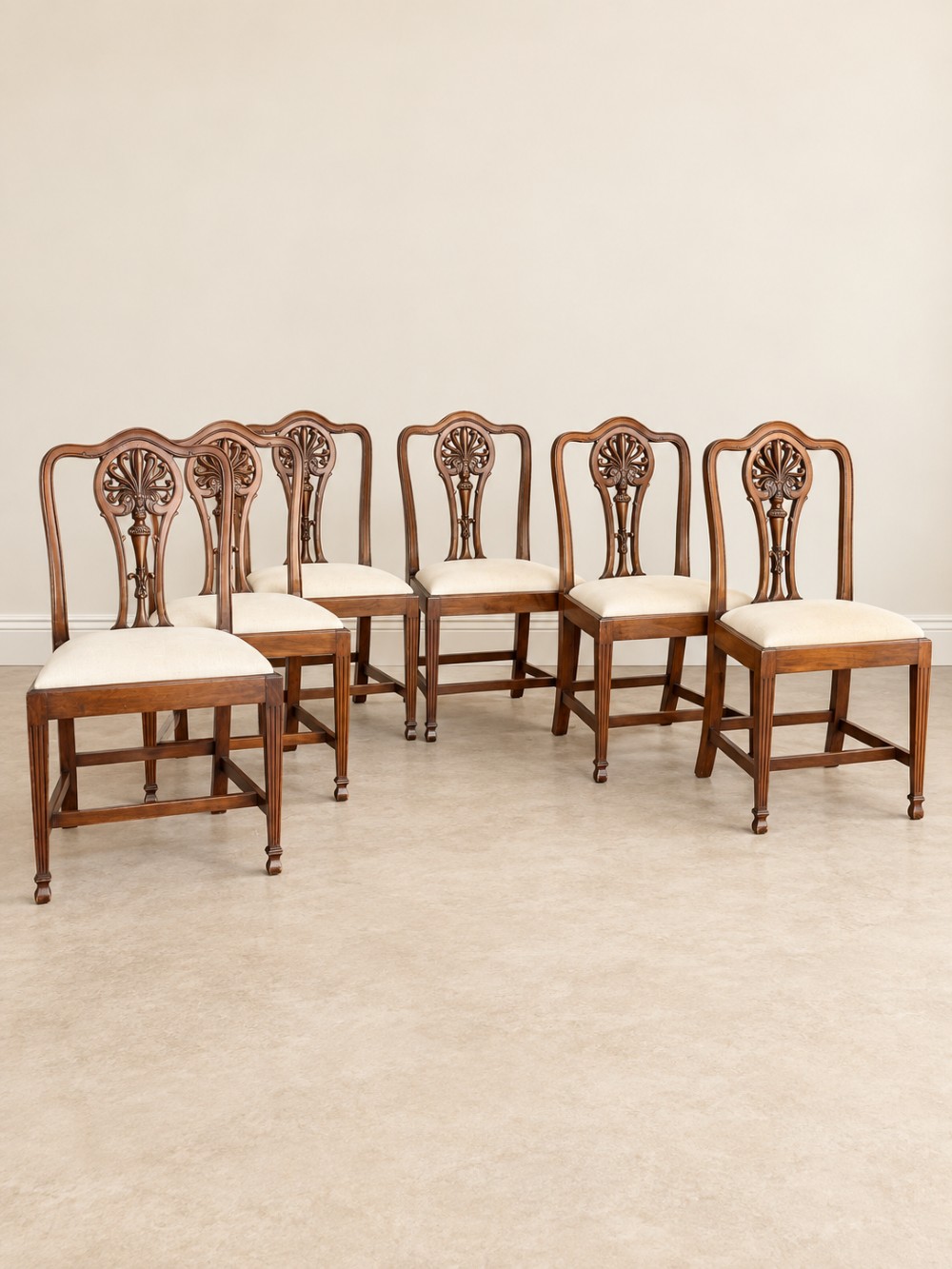 A set of six mahogany dining chairs featuring intricate carved splat backs and neutral cream fabric seats. View II