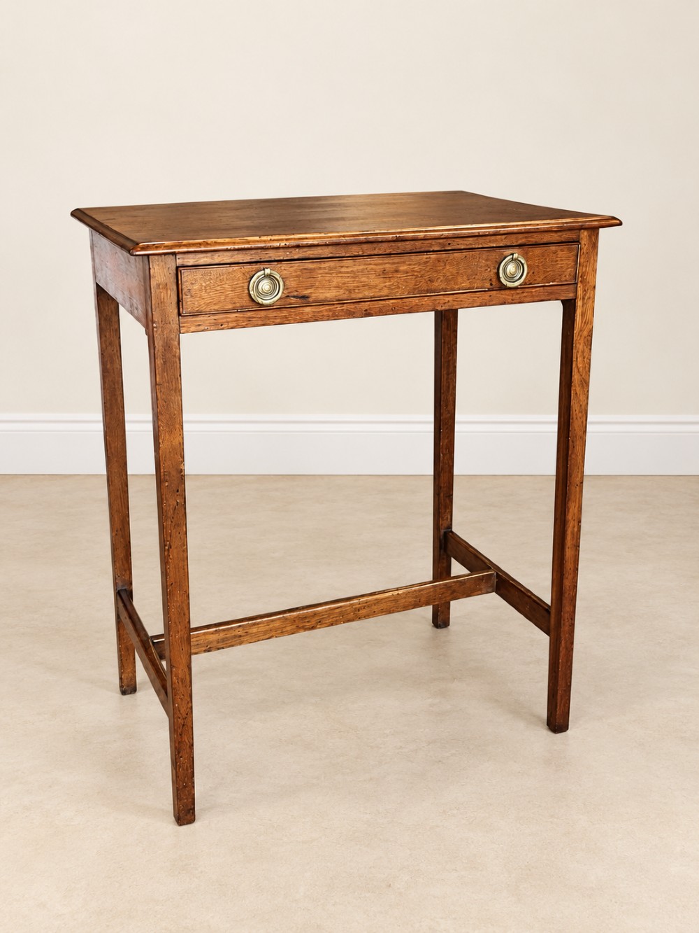 A 19th-century mahogany side table featuring a single drawer with twin brass ring drop handles and straight legs joined by low stretchers.