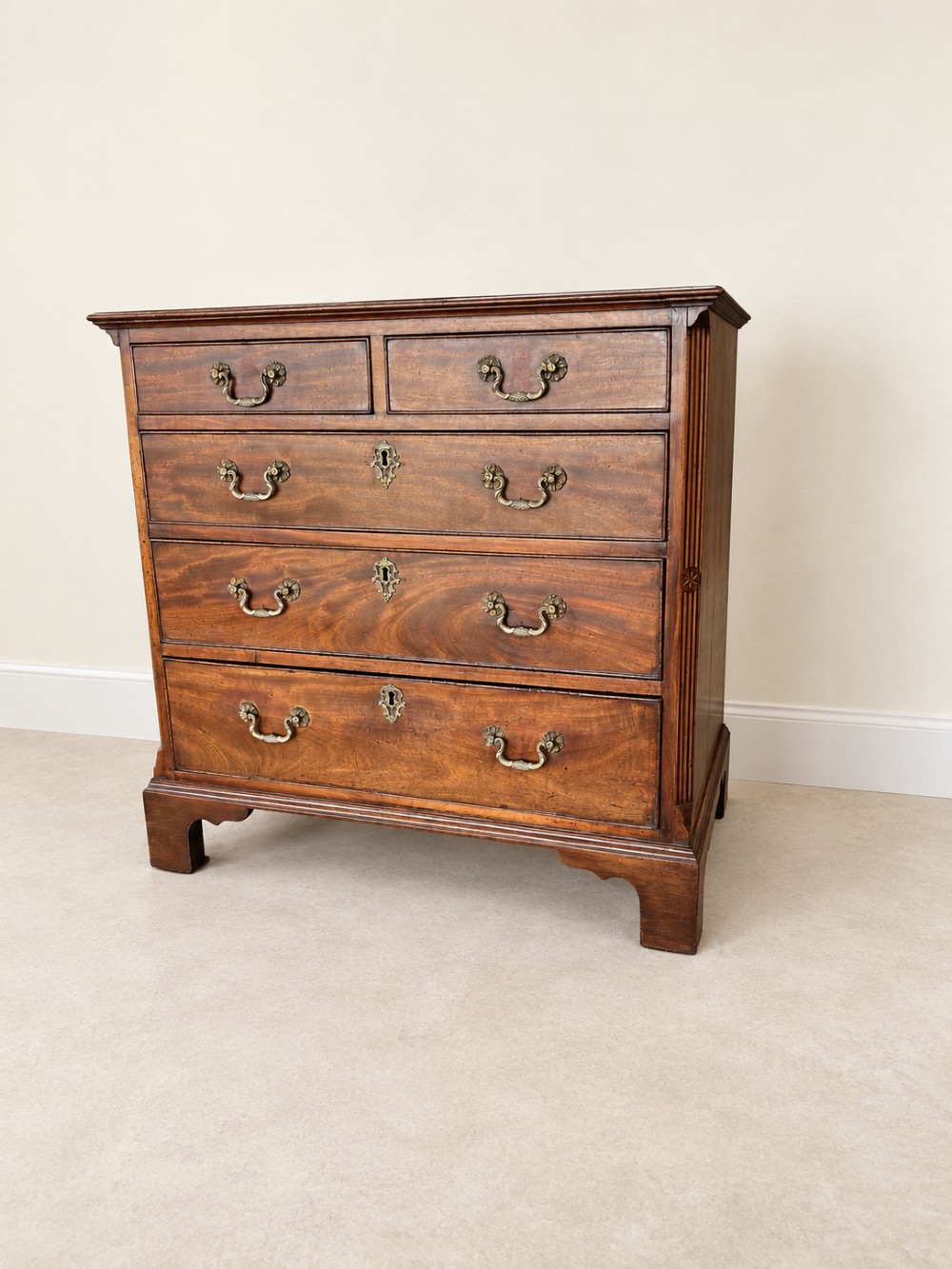An antique George III mahogany chest of drawers featuring two short over three long drawers with decorative brass swan-neck handles and bracket feet. View II