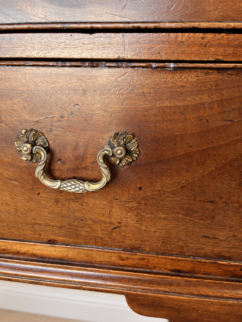 An antique George III mahogany chest of drawers featuring two short over three long drawers with decorative brass swan-neck handles and bracket feet. View VI